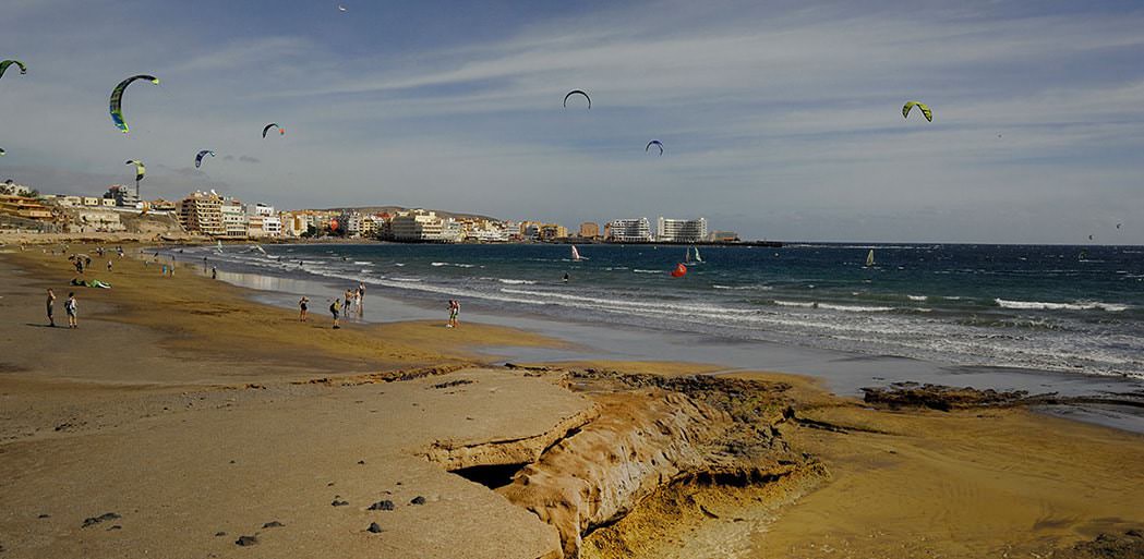 The long natural sandy beach at el Medano, looking at kitesurfers, surfers, walkers and el Medano in the background. Tenerife.